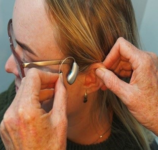 woman placing hearing aid in her ear