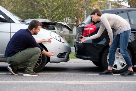 Two people looking at their cars after a car accident
