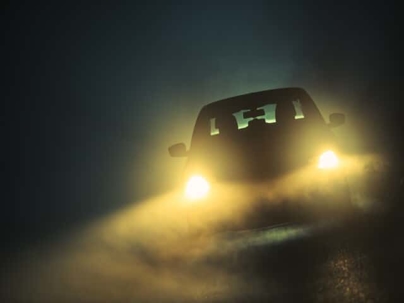 Car driving through night fog